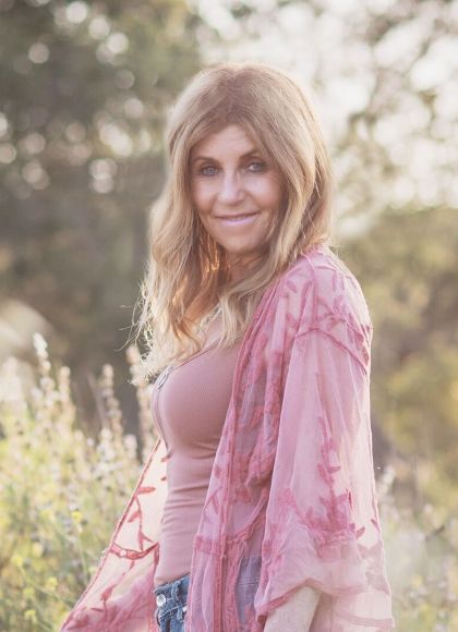 Picture of Patrice Karst smiling and standing in a field.